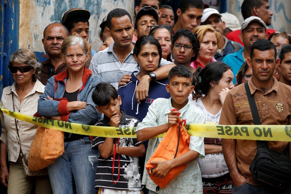 Moradores observam trabalho de investigadores em frente à padaria saqueada em Caracas (Foto: Reuters)