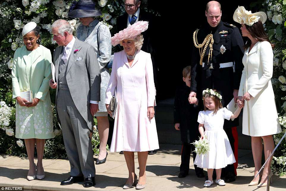 Princess Charlotte is pictured second left with her mother Kate and father William as her brother George hides behind his legs outside St George's Chapel in WindsorÂ 