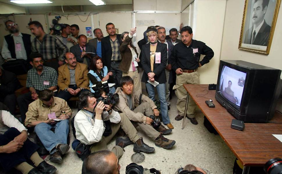 Jornalistas de todo o mundo acompanham pronunciamento do então ditador Saddam Hussein pela TV estatal iraquiana, quatro dias após o início dos bombardeios