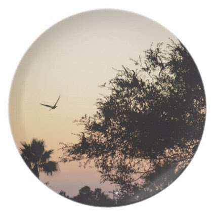 trees and flying bird against florida sunset dinner plate