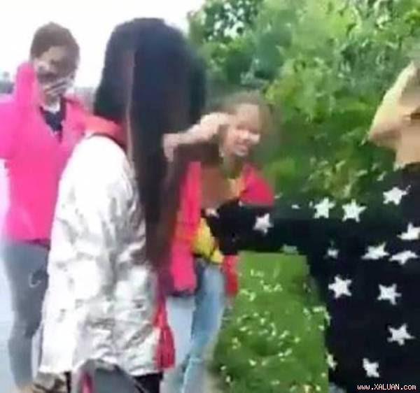  Nữ sinh mặc áo chống nắng đứng im bị hai bạn nữ (mặc áo đen, áo đỏ) tát liên tiếp vào mặt. Ảnh: Cắt từ clip