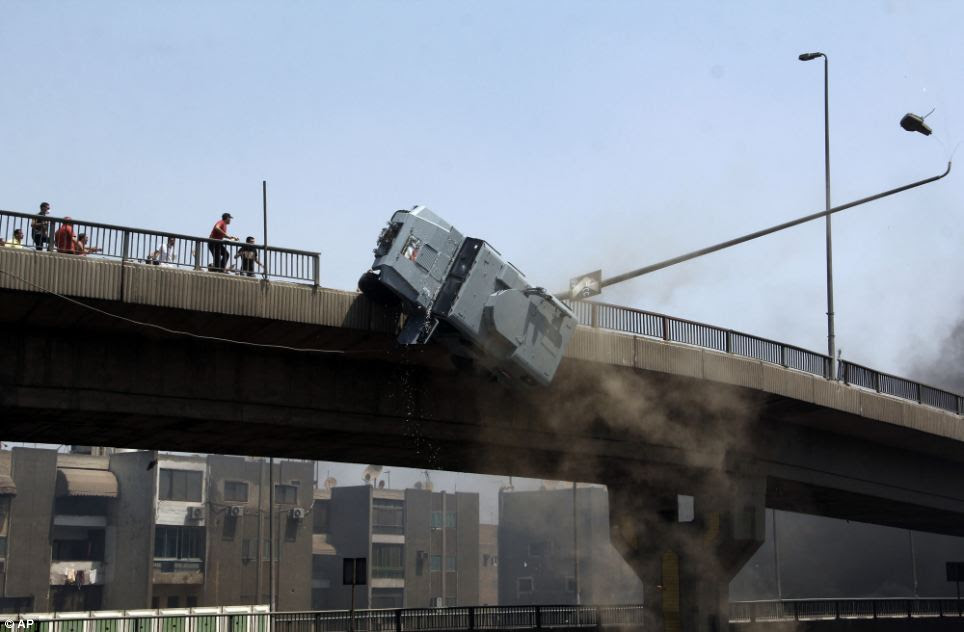 The police vehicle crashes through a fence as it is pushed off the 6th of October bridge in Cairo by protesters as violence in the capital escalated