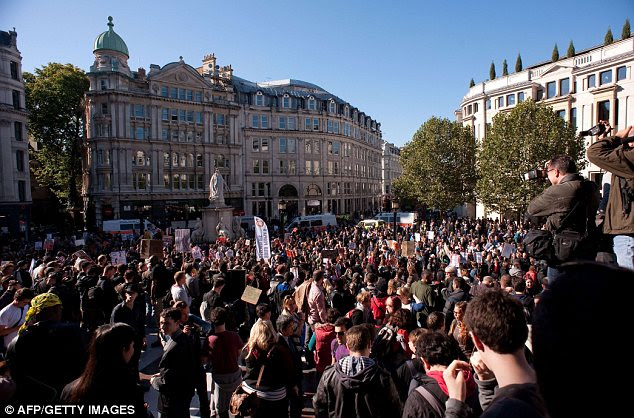 Angry: Protesters hold placards as they stand on the steps of Saint Paul's Cathedral 