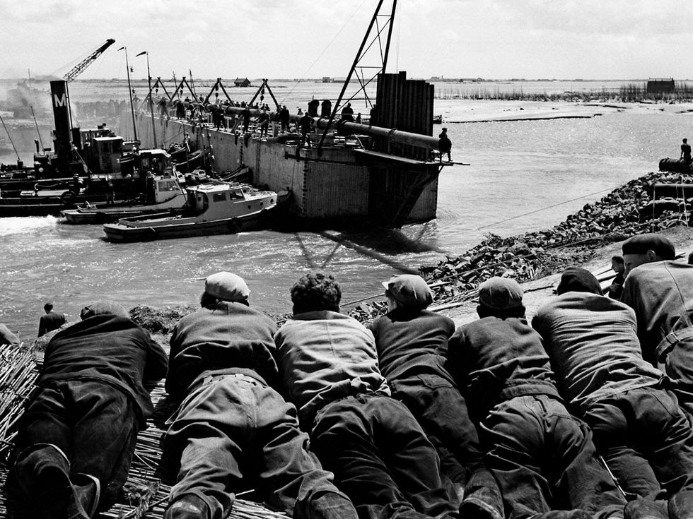 Inwoners van Stevensluis op Schouwen Duiveland bekijken hoe het dijkgat wordt dichtgemaakt.
