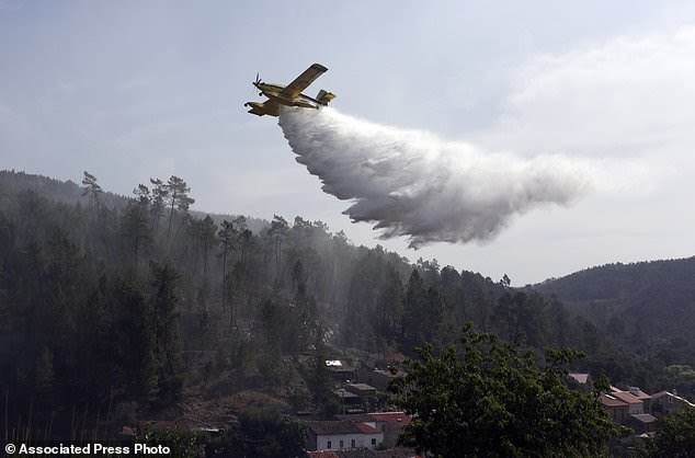 A firefighting plane drops its load to prevent wildfires from reigniting over the village of Agua Formosa, near Vila de Rei, central Portugal, Tuesday, Aug. 15 2017. The small village was evacuated Monday night when raging forest fires approached. Around 3,000 firefighters in Portugal were struggling to put out more than 150 wildfires raging across the country Tuesday, as persistent hot and dry weather stoked the flames, officials said. (AP Photo/Armando Franca)