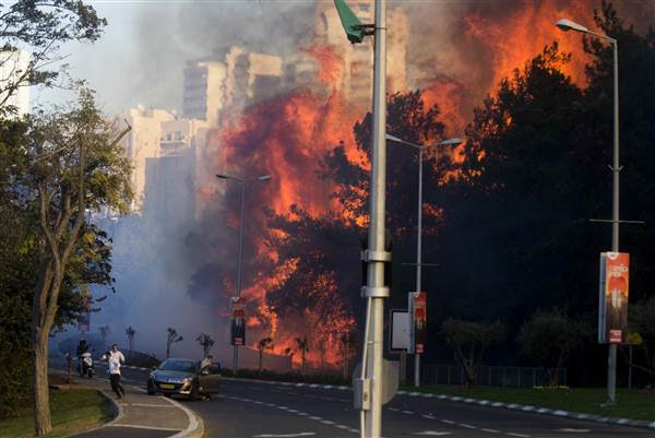 People run as wildfires rages in Haifa, Israel