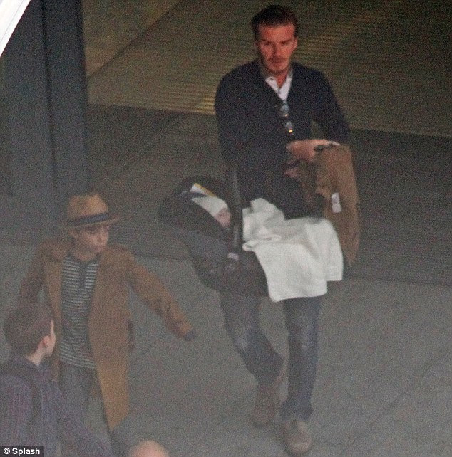 Multitasking: David was seen carrying baby Harper as trendy Romeo walked ahead to the waiting car