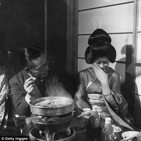 A geisha girl laughing shyly and politely at a joke, circa 1955