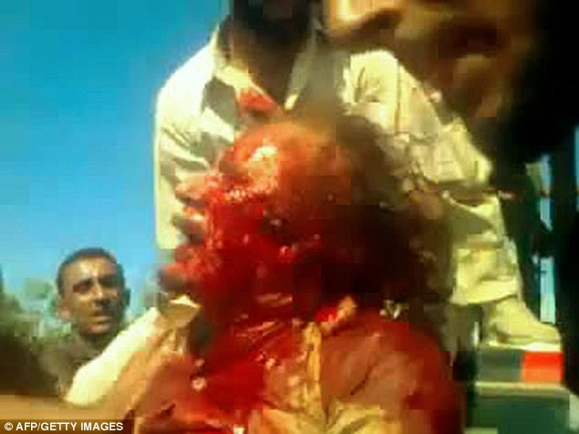 Grimacing in pain: A still from a video taken from the mobile phone of a rebel fighter shows Gaddafi, his face covered in blood, being dragged around by freedom fighters