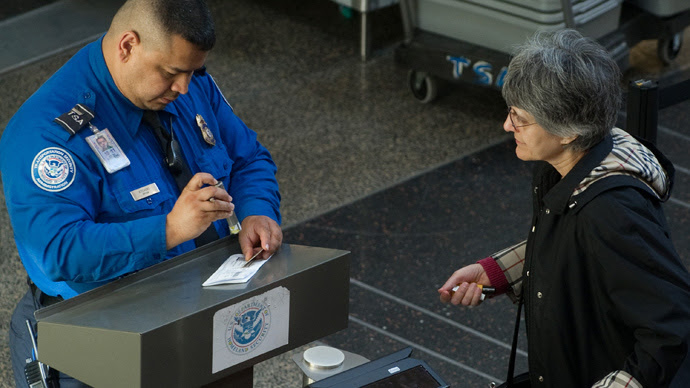 A US Transportation Security Administration (TSA) agent checks the identification and boarding pass of a passenger as she passes through security in the terminal at Ronald Reagan Washington National Airport in Arlington, Virginia (AFP Photo / Saul Loeb) 