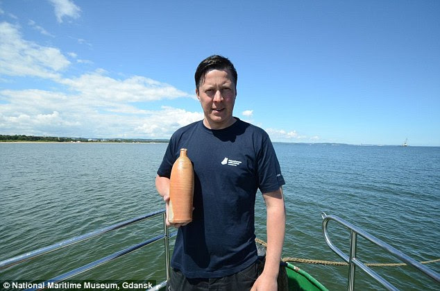 The 19th century corked stoneware bottle is pictured here with underwater archaeologist Tomasz Bednarz