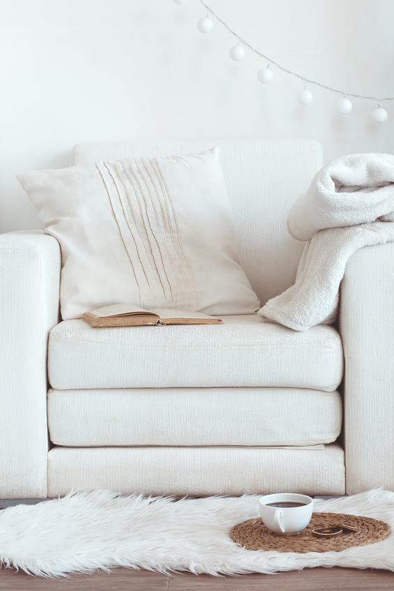 Still life interior details, cup of coffee and a book near white cozy chair