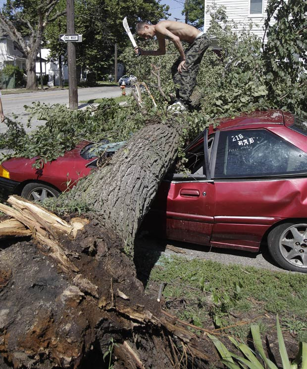A forte tempestade que ocorreu durante a noite na região de Cleveland, no estado americano de Ohio, deixou mais de 25 mil habitantes sem energia elétrica nesta quinta-feira (25). Com a força dos ventos, uma árvore caiu sobre o carro de um morador. Lee Butler usou um facão para tentar cortar o grande tronco que esmagou seu veículo. (Foto: Tony Dejak/AP) A forte tempestade que ocorreu durante a noite na região de Cleveland, no estado americano de Ohio, deixou mais de 25 mil habitantes sem energia elétrica nesta quinta-feira (25). Com a força dos ventos, uma árvore caiu sobre o carro de um morador. Lee Butler usou um facão para tentar cortar o grande tronco que esmagou seu veículo. (Foto: Tony Dejak/AP)