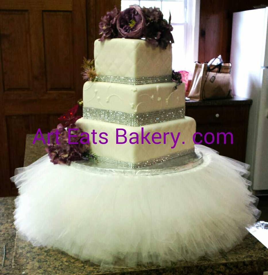 Three tier custom designed unique white fondant wedding cake with diamond embossing and fabric stand.jpg