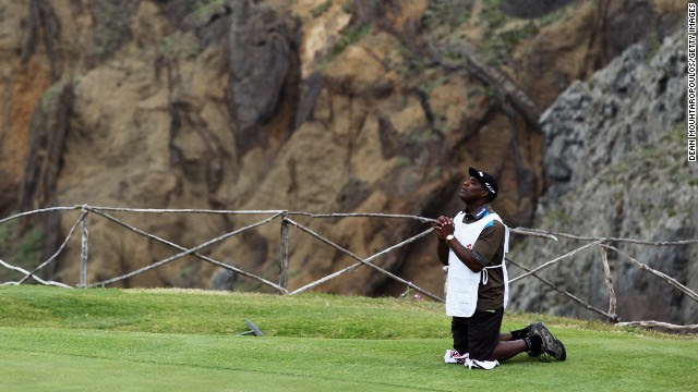 Hugo Benson, caddy of Finnish golfer Roope Kakko, kneels down on the 14th green and prays during the final round of the 2011 Madeira Islands Open.