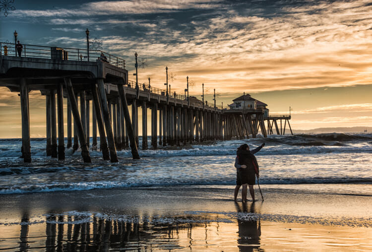 The couple taking a selfie is placed in a rule of thirds position and fills a negative space on the beach.