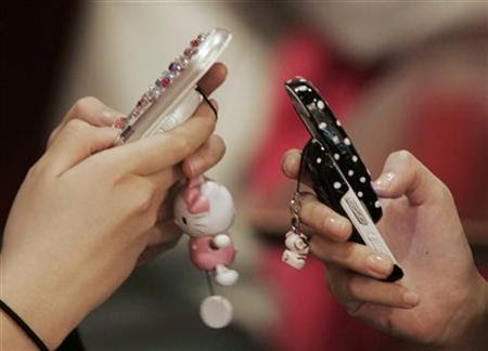 Middle-school girls use mobile phones as they chat in a restaurant in Seoul December 15, 2006. REUTERS/Kim Kyung-Hoon