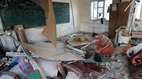 A Palestinian collects body parts in a classroom at the Abu Hussein UN school in Jebaliya refugee camp, northern Gaza Strip, hit by an Israeli strike on Wednesday. (Source: AP)