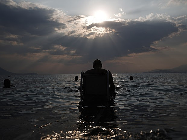  Lefteris Theofilou, de 52 anos, que sofre de paraplegia, entra no mar com a ajuda do "Seatrac", dispositivo movido a energia solar que permite pessoas com deficiência entrem e saiam do mar de forma autônoma, em praia de Alepochori, no oeste de Atenas, no dia 12 de julho  (Foto: Yorgos Karahalis/Reuters)
