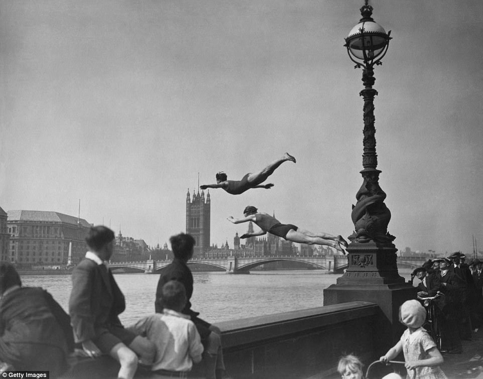 Two divers jumping off the Embankment into the River Thames in London, near Westminster Bridge