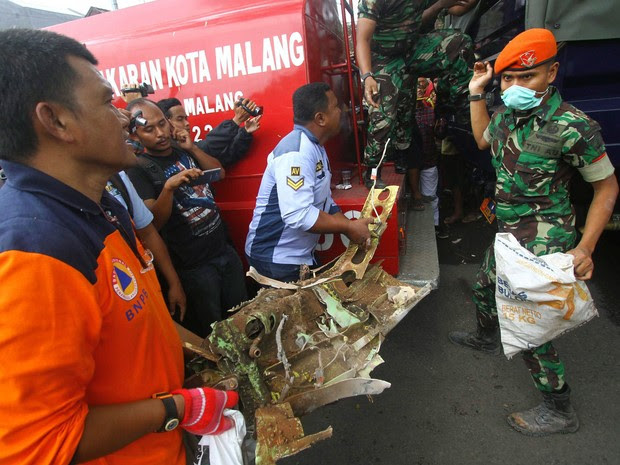 Equipes de resgate carregam uma parte do avião indonésio da Força Aérea na Indonésia, nesta quarta-feira (10). (Foto: AP)