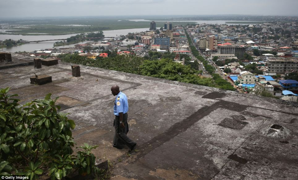 A security guard walks atop the roof of an abandoned hotel in Monrovia