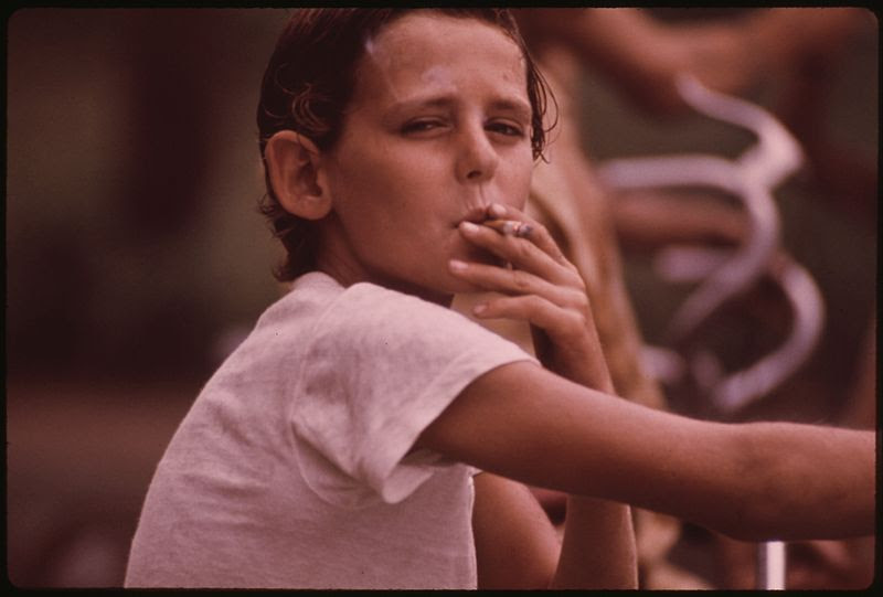 File:DONNY, A NEIGHBORHOOD YOUNGSTER, DRAGS ON A CIGARETTE PASSED TO HIM BY AN OLDER BOY - NARA - 553505.jpg