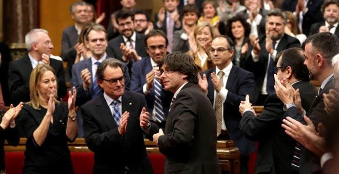 El nuevo presidente de la Generalitat, Carles Puigdemont (c), tras ser elegido durante el pleno de investidura celebrado esta tarde en el Parlament de cataluña. EFE/Alberto Estévez