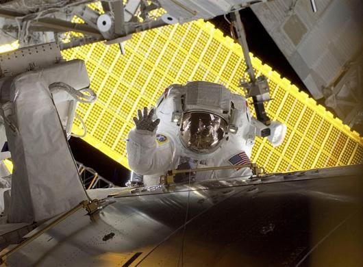 Astronaut Nicole Stott, STS-128 mission specialist waves as she pauses during the mission's first spacewalk with the International Space Station's solar panels as a backdrop as construction and maintenance continue on the International Space Station in this NASA handout photo taken September 1, 2009. REUTERS-NASA-Handout 