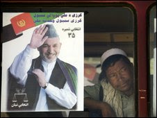 An Afghan man peers trough the window of a bus decorated with electoral posters 