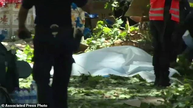 A body lies on the covered on the ground after a falling tree killed people near Funchal on the island of Madeira Portugal in this image taken from video Tuesday Aug.15, 2017.  Portuguese media has reported that people  died when they were crushed by a falling tree during at a popular religious festival on the island of Madeira. (TVI via AP)