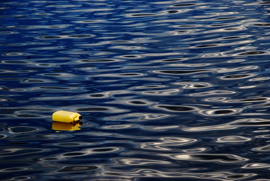 A yellow bottle floating on blue water.