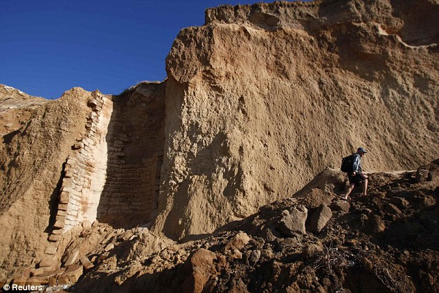 Lost forever: A man walks near an ancient well that crumbled on the shore of the Mediterranean in Ashkelon in the same storm that uncovered the statue