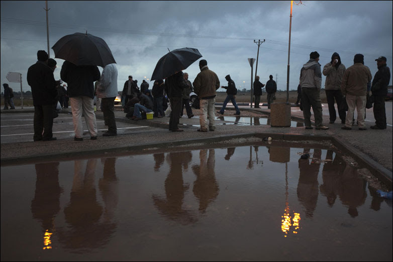 Palestinian workers waiting for transportation at an Israeli checkpoint