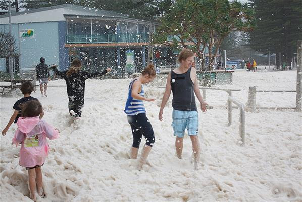 Warga bermain di derasnya banjir di tepi pantai kota Burleigh, Queensland, Australia, 28/1.