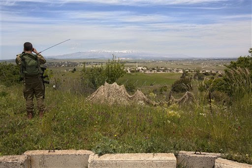 An Israeli soldier looks through binoculars at a Syrian village from an army post on the border between Israel and Syrian on the Golan Heights (photo credit: AP Photo/Sebastian Scheiner)