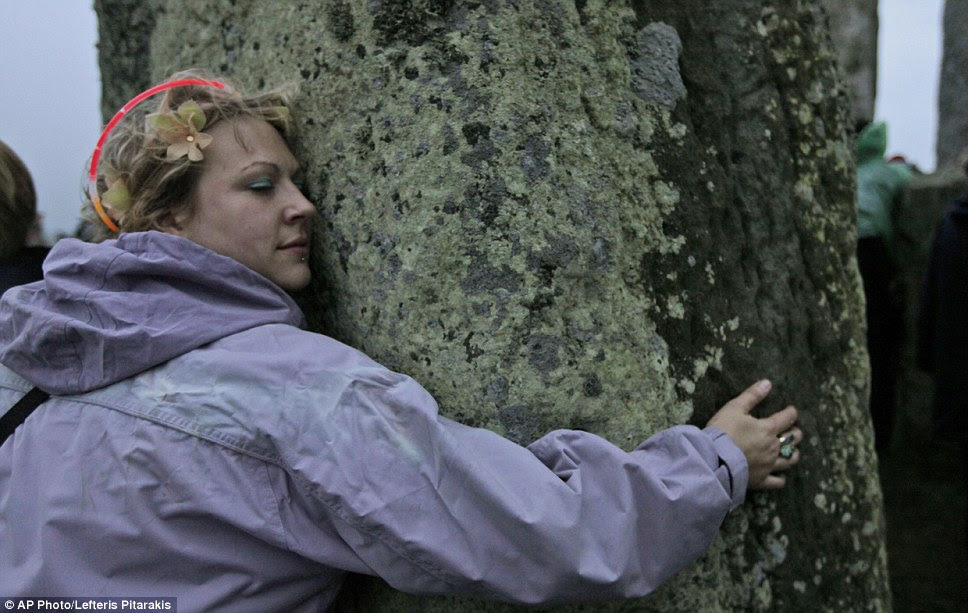 Getting close to nature: A woman hugs a stone at Stonehenge