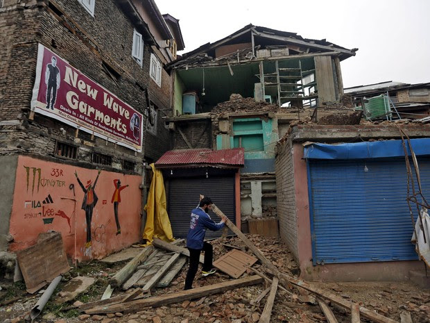 Homem retira destroços após casa desabar parcialmente após terremoto atingir Srinagar, na Índia, no domingo (10) (Foto: Danish Ismail/Reuters )