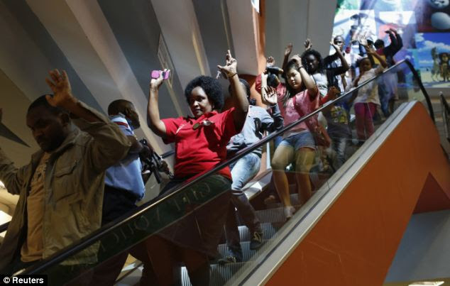 Horror: Shoppers hurry down an escalator with their hands in the air as they make their way out of the shopping centre to safety