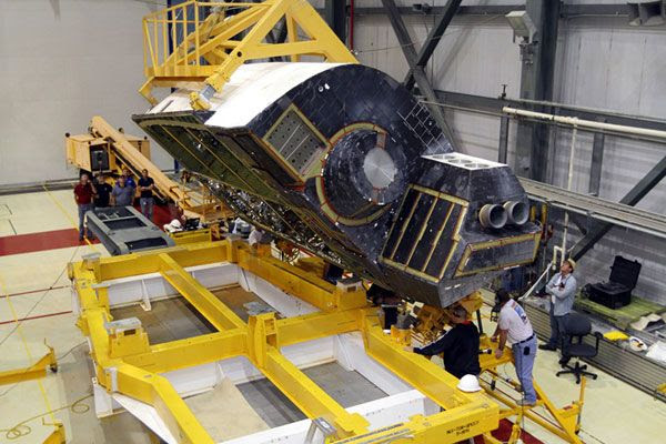 The right OMS pod is lifted from its trailer for re-installation onto Endeavour on March 28, 2012.