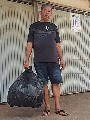 O pedreiro aposentado Benício Eleutério com a carteira que perdeu ao jogar fora saco de lixo e que lhe foi devolvida por estudante (Foto: Raquel Morais/G1)