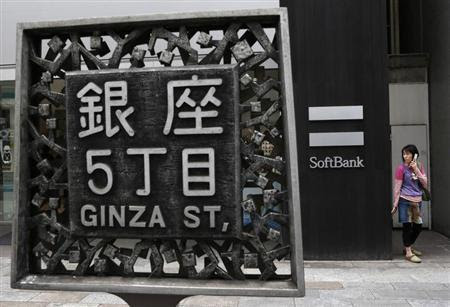 A woman holding a mobile phone stands in front of Softbank Corp's branch in Tokyo April 17, 2013. REUTERS/Yuya Shino