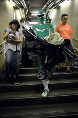 Pahwalan super hero Tadahiro membantu membawa kereta bayi di salah satu lorong stasiun bawah tanah Tokyo.