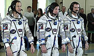 Canadian astronaut Chris Hadfield, right, stands with U.S. astronaut Thomas Marshburn, left, and Russian cosmonaut Roman Romanenko before their final preflight practical examination in a mockup of a Soyuz TMA spacecraft at the Russian Space Training Center in Star City, Russia, on Nov. 28, 2012.