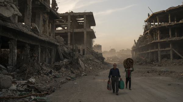 Two civilians carry belongings they collected from their damaged house in the Old City of Mosul, Iraq. The Islamic State controlled the northern Iraqi city for three years before being driven out last year. ISIS no longer controls any cities, but small groups of fighters remain in Iraq and Syria, and are still considered a threat.