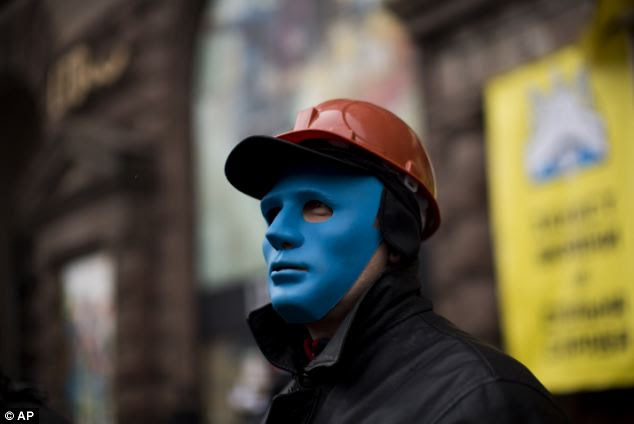 An opposition protester protects the entrance of a shop occupied by demonstrators still camped out on Kiev's Independence Square