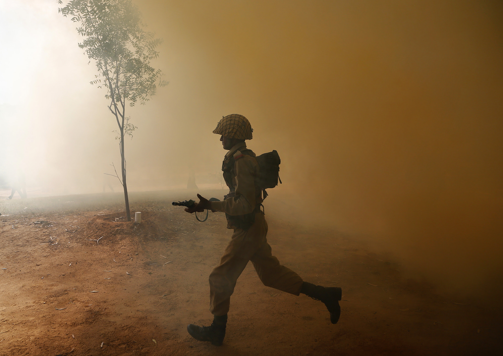 An Indian army soldier runs amid smoke from canisters during a session to showcase skills at the Army Service Corps training centre in Bangalore, India, Monday, Dec. 5, 2016. (AP Photo/Aijaz Rahi)