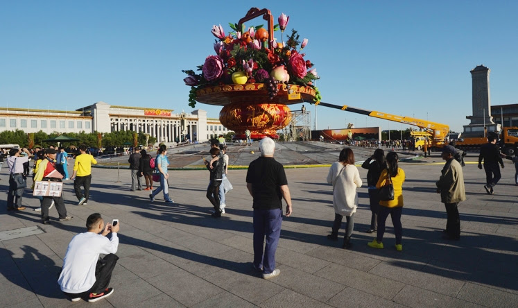 Pekerja sedang memasang rangkaian bunga dan buah pir palsu disaksikan warga Beijing.