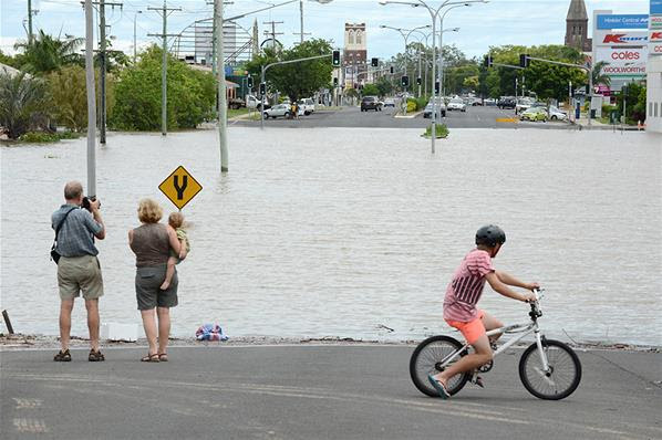 Warga menyaksikan luapan banjir yang menutup jalan utama di Bundaberg, Australia, Queensland, 28/1.