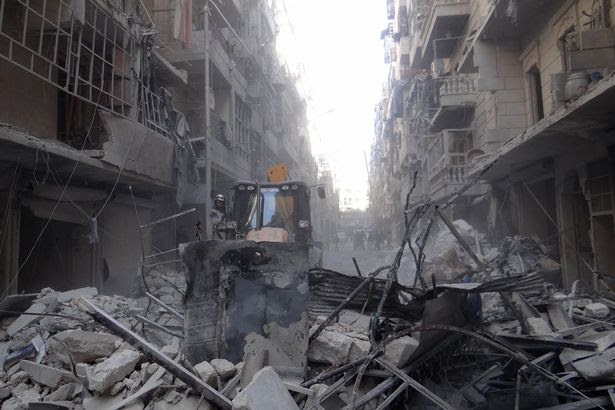 A construction vehicle tries to clear the debris of collapsed buildings